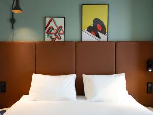 a bedroom with a bed with two pillows and paintings at ibis Paris Gare de Lyon Reuilly in Paris +32 photos