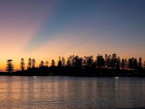 a sunset over a lake with trees in the background at The Sebel Kiama in Kiama