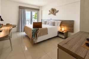 a hotel room with a bed and a desk and a window at SERHS Beach Hotel in Natal