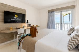 a bedroom with a bed with a desk and a television at SERHS Beach Hotel in Natal