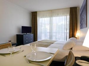a hotel room with a bed and a table with plates on it at Aparthotel Adagio Nice Promenade des Anglais in Nice