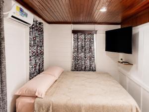 a small bedroom with a bed and a flat screen tv at Miss Titi's Native Lodge in San Andrés