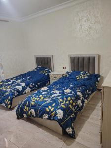 two beds in a room with blue and yellow comforter at الرائد للشقق المفروشة in Amman
