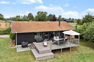 a house with a deck with a table and an umbrella at 7032-Bogo-Kvaernen-32 in Gammelby