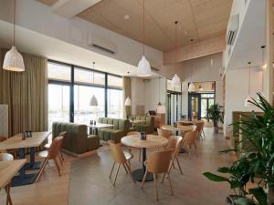 a restaurant with tables and chairs and windows at Guesthouse Leithagebirge in Breitenbrunn