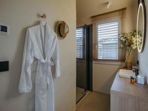 a white robe hanging on a wall in a bathroom at Guesthouse Leithagebirge in Breitenbrunn