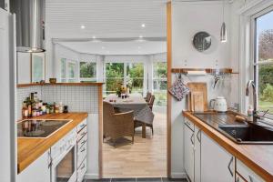 a kitchen with white cabinets and a dining room with a table at 1111-Stege-Ulvshalevej-111 in Stege +18 photos