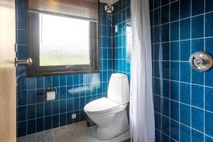 a blue tiled bathroom with a toilet and a window at 7041-Bogo-By-Tarnbakken-21 in Bogø By +18 photos