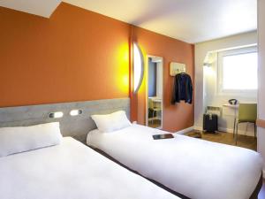 two beds in a room with orange walls at ibis budget Vienne Sud in Vienne +36 photos
