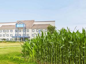 a large white building with a blue sign on it at ibis budget Santeny in Santeny