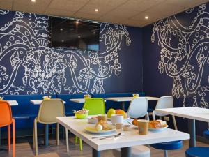 a dining room with tables and chairs and a mural at Ibis Budget Marseille Timone in Marseille
