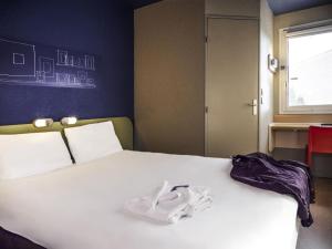 a bedroom with a white bed with shoes on it at ibis budget Arles Sud Fourchon in Arles