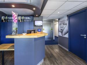 an office with a reception counter with a vase of flowers at Ibis Budget Montelimar in Montélimar +41 photos