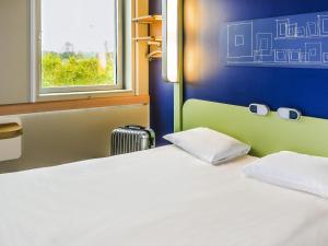 a bedroom with a white bed and a window at Ibis Budget Montelimar in Montélimar