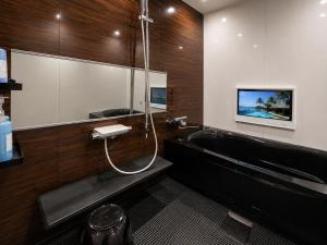 a bathroom with a bath tub and a tv at Hotel BaliBali 仙台 in Kōtōdaitōri