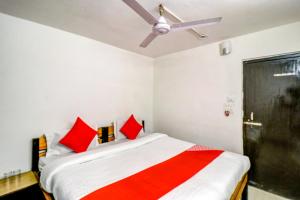 a bedroom with a bed with red pillows and a ceiling fan at Hotel O by OYO Dhruv Inn in Izatnagar