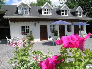 a white house with pink flowers in front of it at Gorgeous Apartment in Bohon with Garden Furniture and BBQ in Barvaux