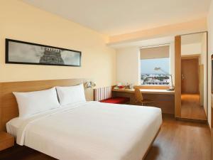 a bedroom with a white bed and a desk and a window at ibis Coimbatore City Centre - An Accor Brand in Coimbatore +91 photos