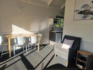 a living room with a table and chairs and a kitchen at Ohope Beach Motel in Ohope Beach +10 photos