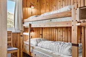 two bunk beds in a wooden room with a television at 4468-Hvide-Sande-Tingodden-427 in Hvide Sande