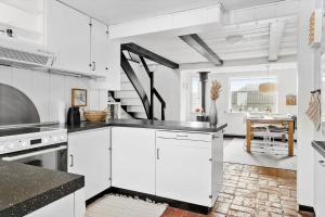 a kitchen with white cabinets and a dining room with a table at 724-Thyboron-Kirkevej-9 in Thyborøn +19 photos