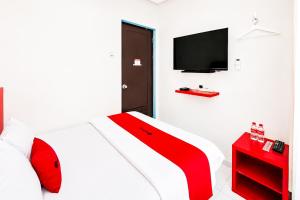 a bedroom with a bed with a tv on the wall at RedDoorz @ Galuh Mas in Karawang
