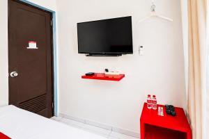 a bedroom with a flat screen tv on the wall at RedDoorz @ Galuh Mas in Karawang +13 photos