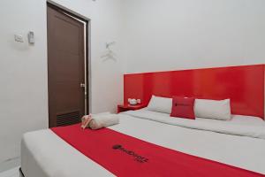 two beds in a room with a red headboard at RedDoorz @ Galuh Mas in Karawang
