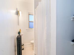 a bathroom with a toilet and a white shower curtain at High Falls Studio TV Kitchen Downtown Rochester in Rochester