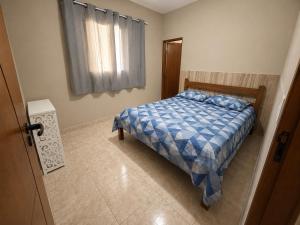 a bedroom with a bed with a blue comforter and a window at sitio sonho verde in Serra Negra +19 photos