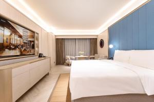 a hotel room with a large bed and a television at Orange Crystal Hotel Kunming Wanda Plaza in Kunming