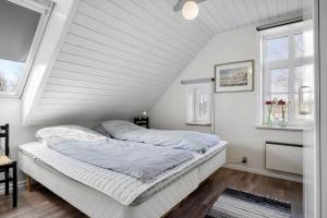 a bed in a room with white walls and windows at 0057-Romo-Juvrevej-49 in Høm