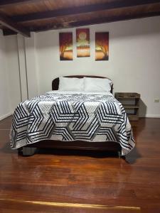 a bed with a black and white comforter in a bedroom at MY HOUSE IN MACAS, SUITE AMOBLADA in Macas
