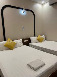 two beds with yellow pillows in a room at Hoàng Long 2 Hotel in Chúc Sơn