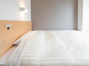 a bed in a bedroom with a white bedsheet at Super Hotel Kokuraeki Minamiguchi in Kitakyushu