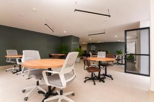 an office with wooden tables and white chairs at Metropolitan Living by HOUSY in Medellín