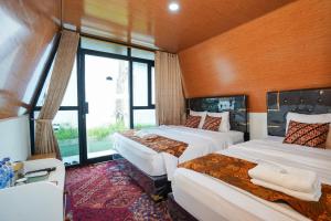 a bedroom with two beds and a large window at The Lavana Astungkara in Beran-kidul