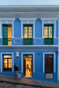 a man riding a skateboard in front of a blue building at Casa Aura Hotel in Bogotá