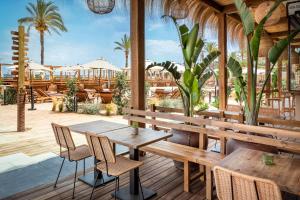 a restaurant with wooden tables and chairs and palm trees at INNSiDE by Meliá Wave Calviá in Magaluf