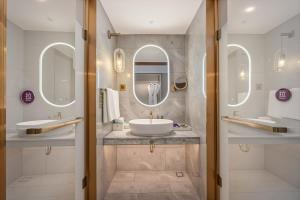 a bathroom with two sinks and two mirrors at Mercure Hefei Huaihe Road in Hefei +70 photos