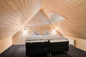a bed in a room with a wooden ceiling at 2503-Romo-Hattesvej-38 in Høm