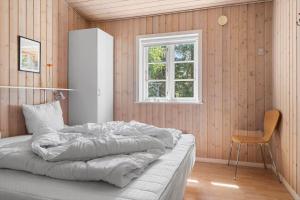 a bed in a room with a window and a chair at 2608-Romo-Sonderstrandvej-18 in Høm