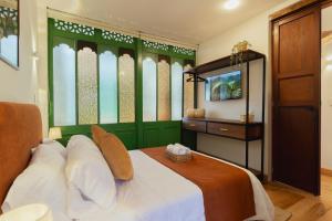 a bedroom with a bed with green walls and a television at Casa Aura Hotel in Bogotá