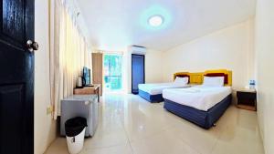 a hotel room with two beds and a television at Vista Residence Patong in Patong Beach