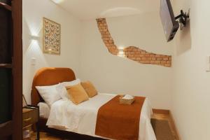 a bedroom with a bed and a tv on the wall at Casa Aura Hotel in Bogotá