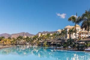 a pool at a resort with palm trees and buildings at Gran Meliá Palacio de Isora Resort & Spa in Alcalá