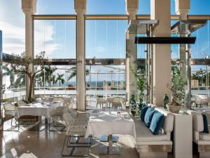 a restaurant with white tables and chairs and large windows at Gran Meliá Palacio de Isora Resort & Spa in Alcalá