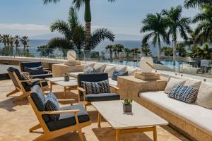 a patio with tables and chairs and the ocean at Gran Meliá Palacio de Isora Resort & Spa in Alcalá