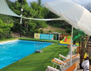 a swimming pool with chairs and an umbrella at Pocheon Yolafongta Pension in Pocheon