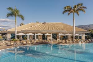 a resort with a swimming pool with chairs and palm trees at RedLevel at Gran Meliá Palacio de Isora - Adults Only in Alcalá +134 photos